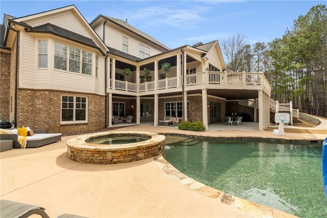 rear view of property featuring a patio, brick siding, a pool with connected hot tub, stairway, and a wooden deck