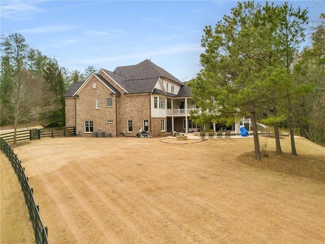 back of house with brick siding, a patio area, fence, a balcony, and cooling unit