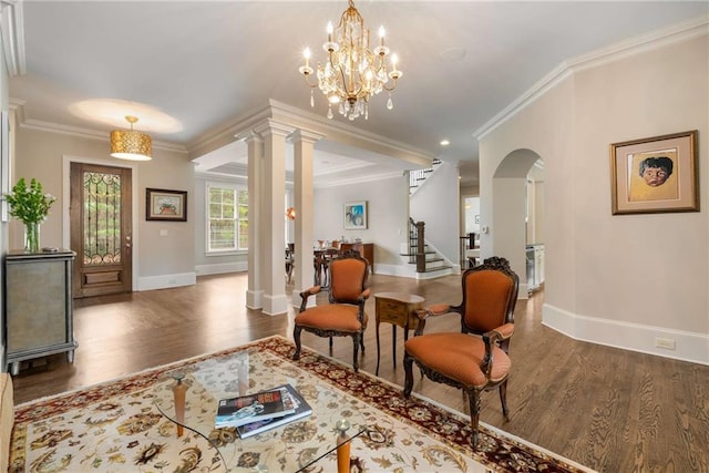 sitting room with decorative columns, arched walkways, wood finished floors, stairs, and crown molding