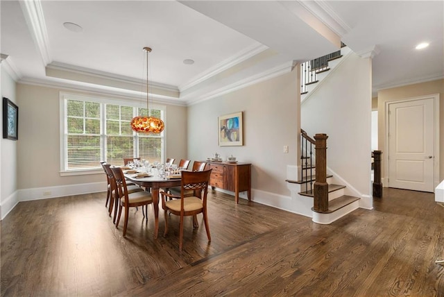 dining area featuring dark wood-style flooring, crown molding, a raised ceiling, baseboards, and stairs