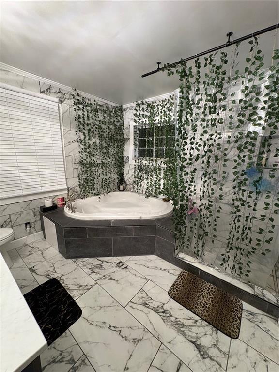 bathroom featuring tile walls, tiled tub, and crown molding