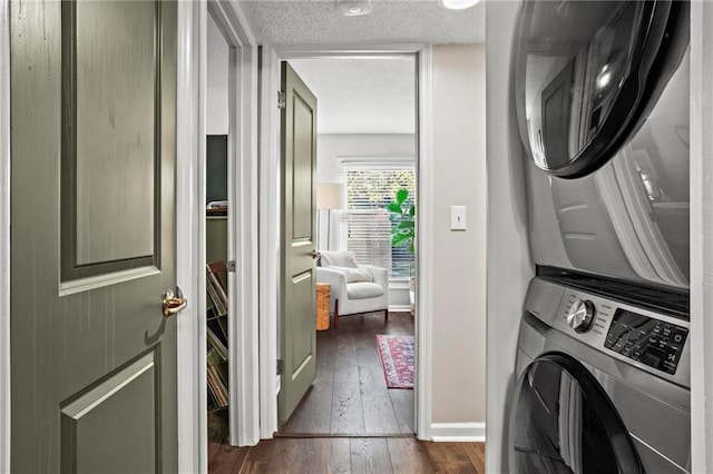 clothes washing area featuring stacked washer and dryer, dark wood-type flooring, and a textured ceiling