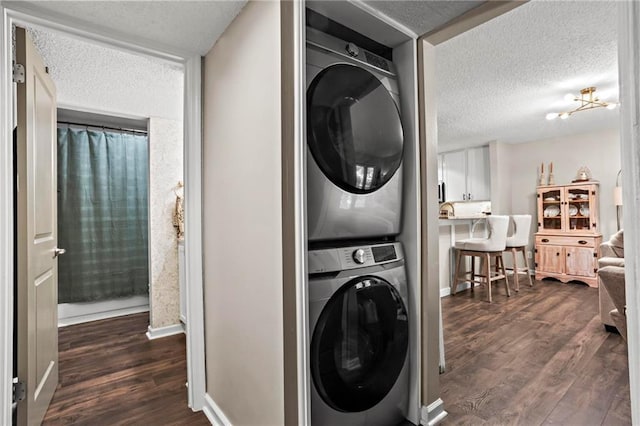 clothes washing area featuring dark hardwood / wood-style flooring, stacked washer / drying machine, and a textured ceiling