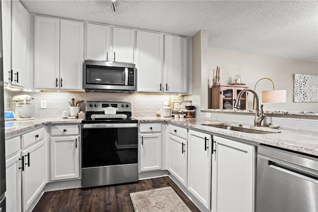 kitchen featuring sink, white cabinetry, light stone counters, a textured ceiling, and appliances with stainless steel finishes