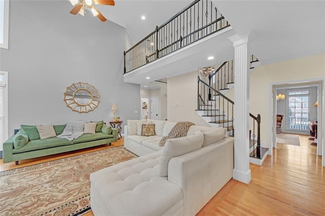 living room featuring light wood-type flooring, stairs, a high ceiling, and recessed lighting