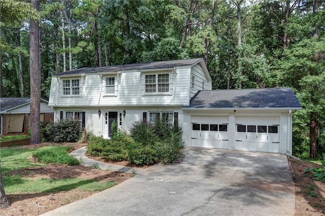 colonial-style house featuring a garage, concrete driveway, and brick siding