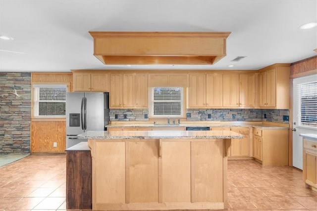 kitchen with visible vents, light brown cabinetry, a center island, stainless steel fridge with ice dispenser, and decorative backsplash