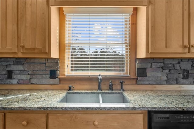 kitchen with dishwasher, light stone counters, tasteful backsplash, and a sink