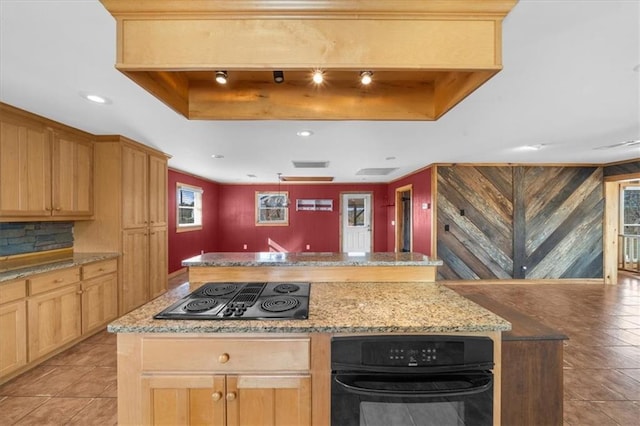 kitchen with a kitchen island, light tile patterned floors, black electric cooktop, a raised ceiling, and light stone countertops