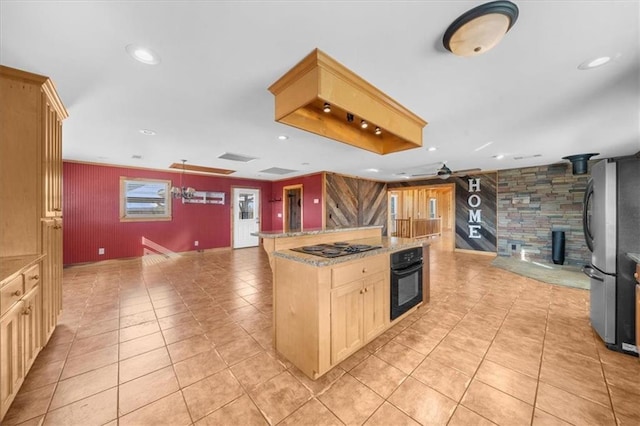 kitchen featuring a wood stove, ceiling fan, black appliances, open floor plan, and a center island