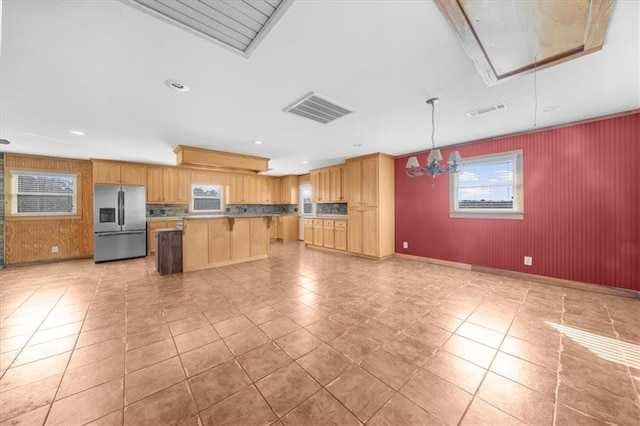 kitchen with a center island, visible vents, stainless steel fridge, and a breakfast bar area