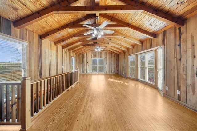 unfurnished living room with hardwood / wood-style floors, wooden walls, vaulted ceiling with beams, and wood ceiling