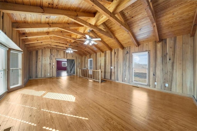 unfurnished living room featuring hardwood / wood-style floors, wooden ceiling, wooden walls, and vaulted ceiling with beams