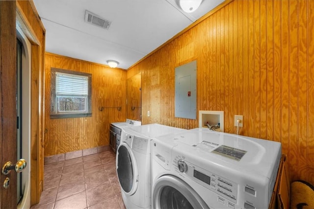 laundry area featuring visible vents, independent washer and dryer, electric panel, wooden walls, and light tile patterned floors