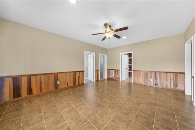 unfurnished room with tile patterned floors, a ceiling fan, recessed lighting, wood walls, and wainscoting