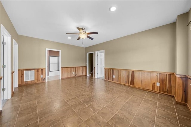 tiled empty room featuring visible vents, ceiling fan, wood walls, recessed lighting, and wainscoting