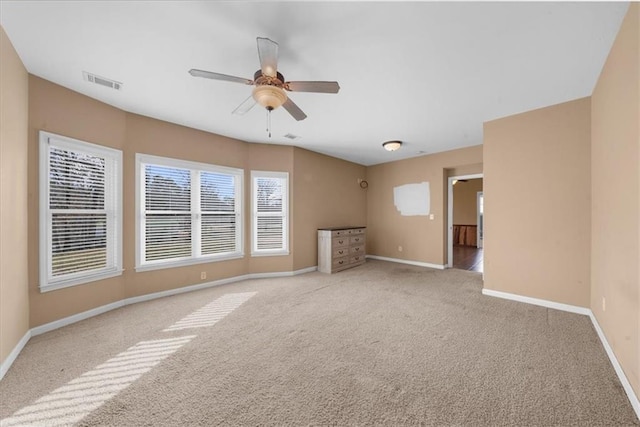 empty room with visible vents, baseboards, carpet, and a ceiling fan