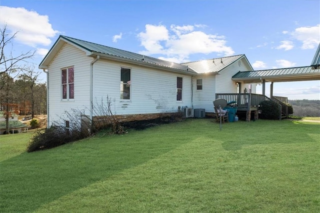 back of house featuring a deck, a lawn, and metal roof