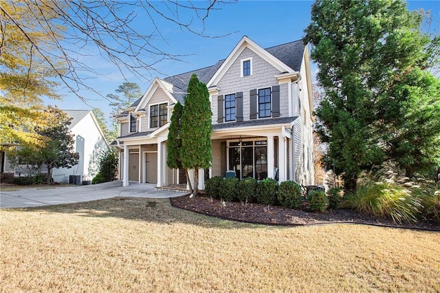 view of front of house featuring cooling unit, a garage, and a front lawn