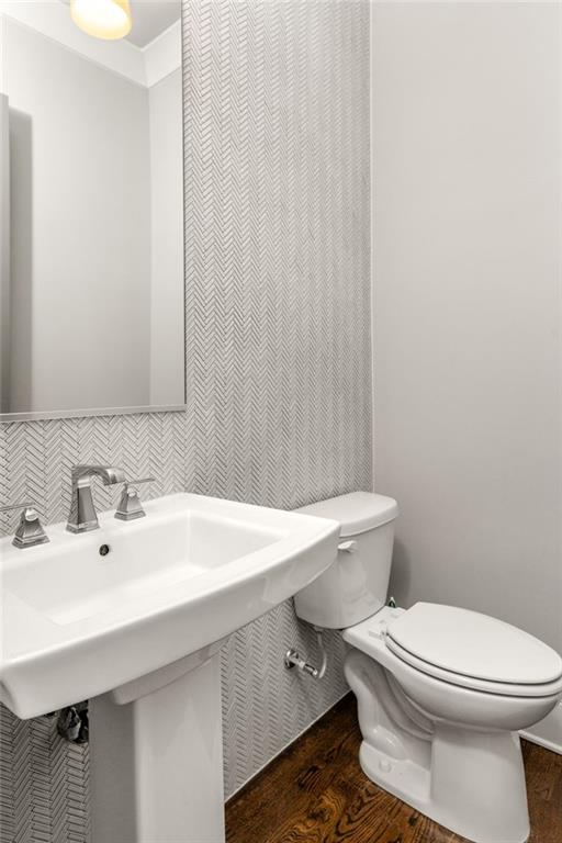 bathroom featuring hardwood / wood-style flooring, toilet, sink, and tile walls