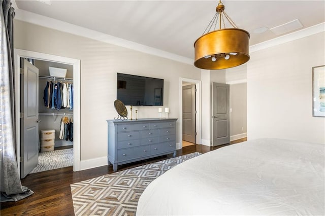 bedroom featuring dark hardwood / wood-style flooring, a walk in closet, ornamental molding, and a closet