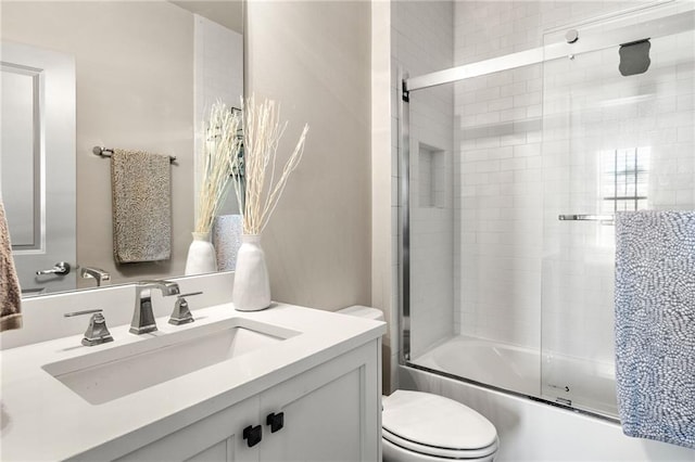 full bathroom featuring enclosed tub / shower combo, vanity, and toilet