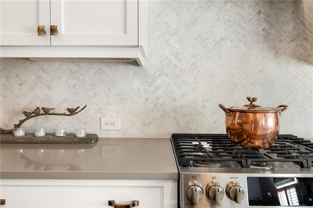 room details featuring white cabinetry, cooktop, and tasteful backsplash