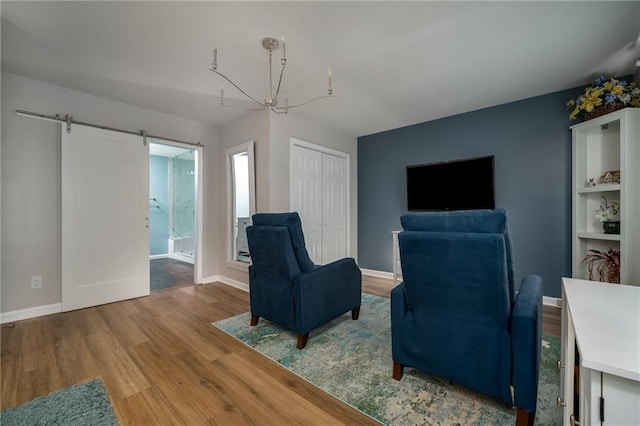 living area featuring a barn door, a notable chandelier, and light hardwood / wood-style flooring