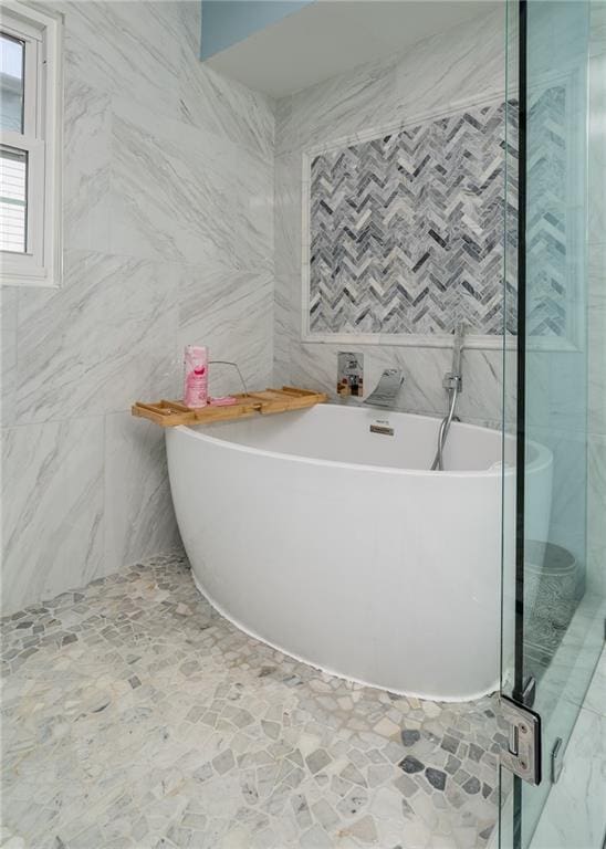 bathroom featuring tile walls and a bathtub