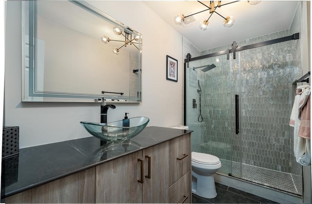 bathroom with a chandelier, vanity, toilet, a shower with door, and tile patterned floors