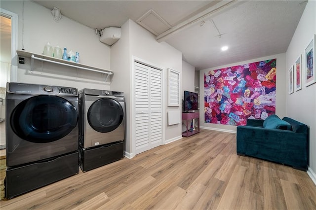 clothes washing area featuring washing machine and dryer and light hardwood / wood-style floors