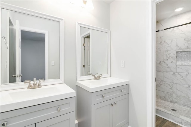 bathroom featuring hardwood / wood-style flooring, vanity, and tiled shower