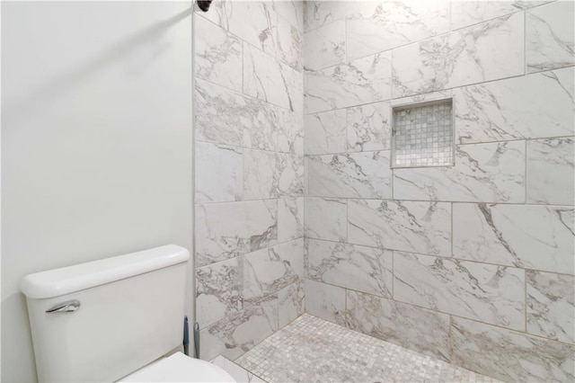 bathroom featuring a tile shower and toilet