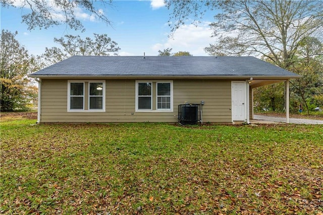 back of property with central AC, a carport, and a lawn