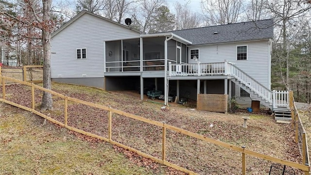 back of property with a sunroom, a shingled roof, fence, and stairway