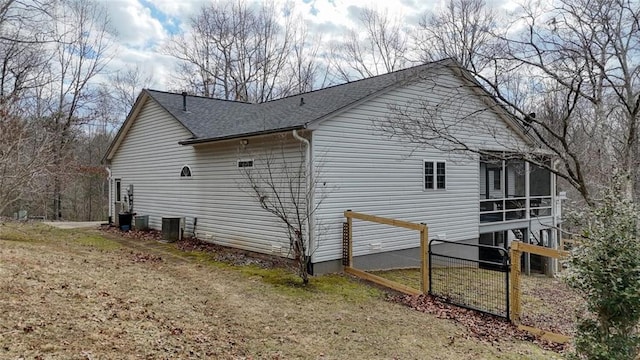 view of side of property with a shingled roof, a sunroom, and central AC