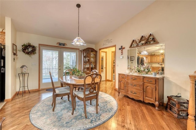 dining area featuring french doors, baseboards, lofted ceiling, and light wood finished floors