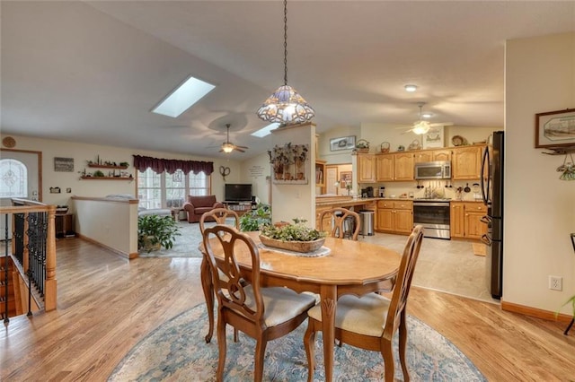 dining space featuring ceiling fan, lofted ceiling with skylight, and light wood finished floors