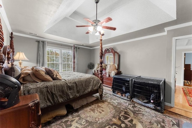 bedroom featuring a raised ceiling, crown molding, hardwood / wood-style flooring, and ceiling fan