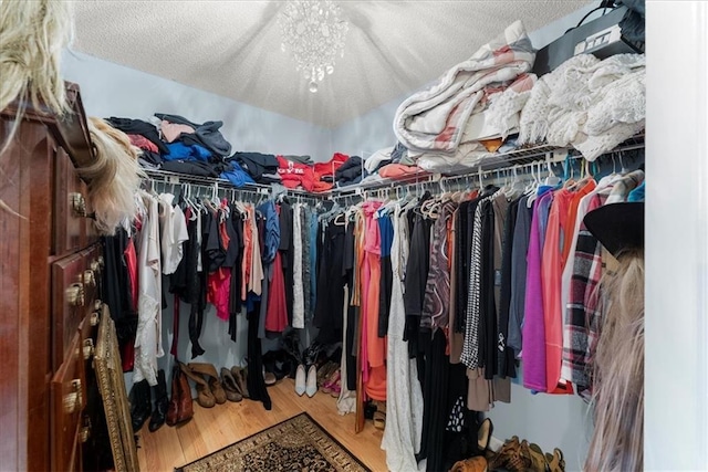 spacious closet with hardwood / wood-style flooring and a chandelier