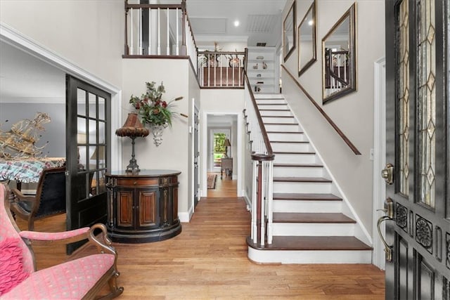 entryway featuring a high ceiling, french doors, light hardwood / wood-style flooring, and crown molding