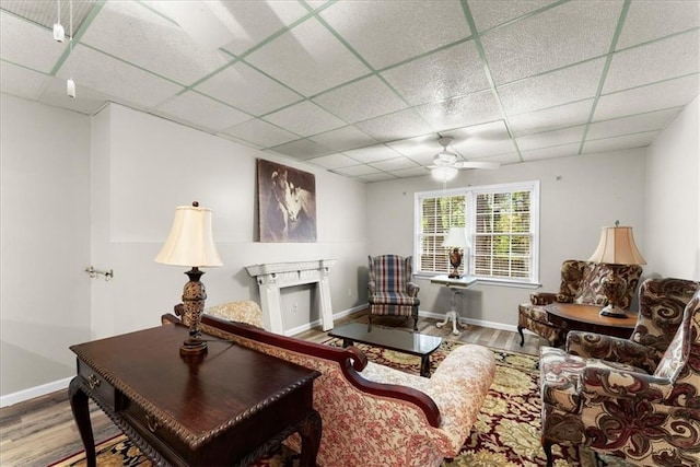 living area with hardwood / wood-style flooring, a paneled ceiling, and ceiling fan