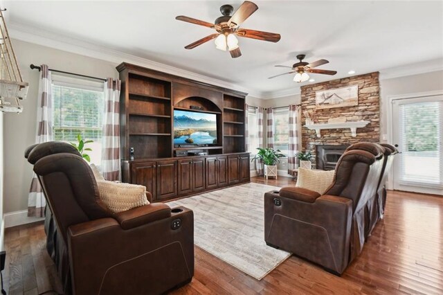 living room featuring ceiling fan, crown molding, dark wood-type flooring, and a fireplace