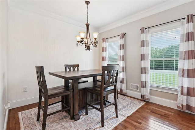 dining room with dark wood-type flooring, crown molding, and an inviting chandelier