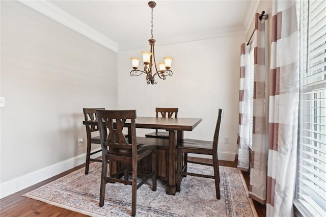 dining room with hardwood / wood-style floors, ornamental molding, and an inviting chandelier