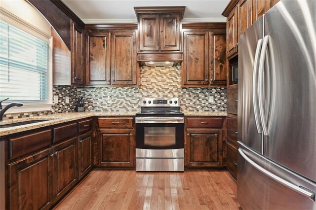 kitchen with sink, light stone counters, appliances with stainless steel finishes, and tasteful backsplash