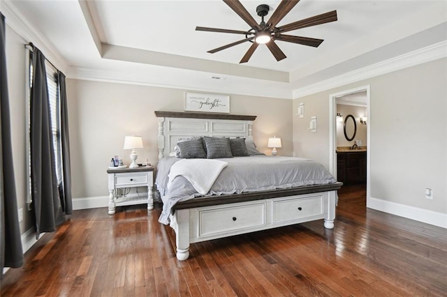 bedroom with ceiling fan, dark wood-type flooring, connected bathroom, and a tray ceiling