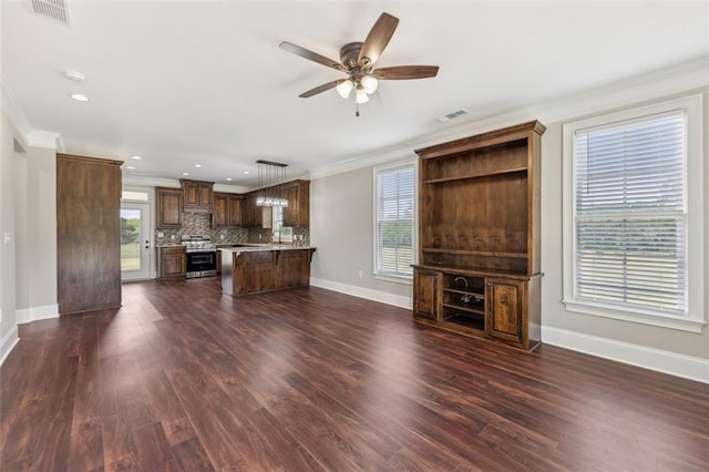 unfurnished living room featuring crown molding, dark wood-type flooring, and a wealth of natural light