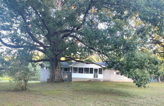 view of front facade with a front yard and a sunroom