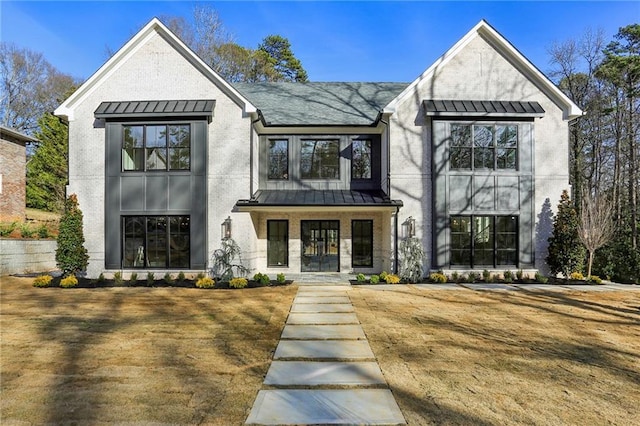 modern inspired farmhouse featuring a standing seam roof, brick siding, and metal roof